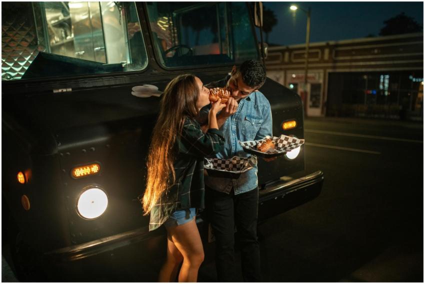 A young couple enjoying food from a truck at night