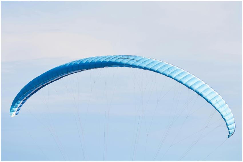 A vibrant blue paraglider soaring high in the sky,