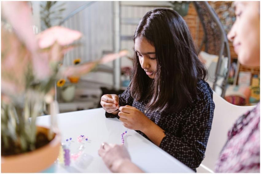 A young girl concentrating on crafting a beaded br