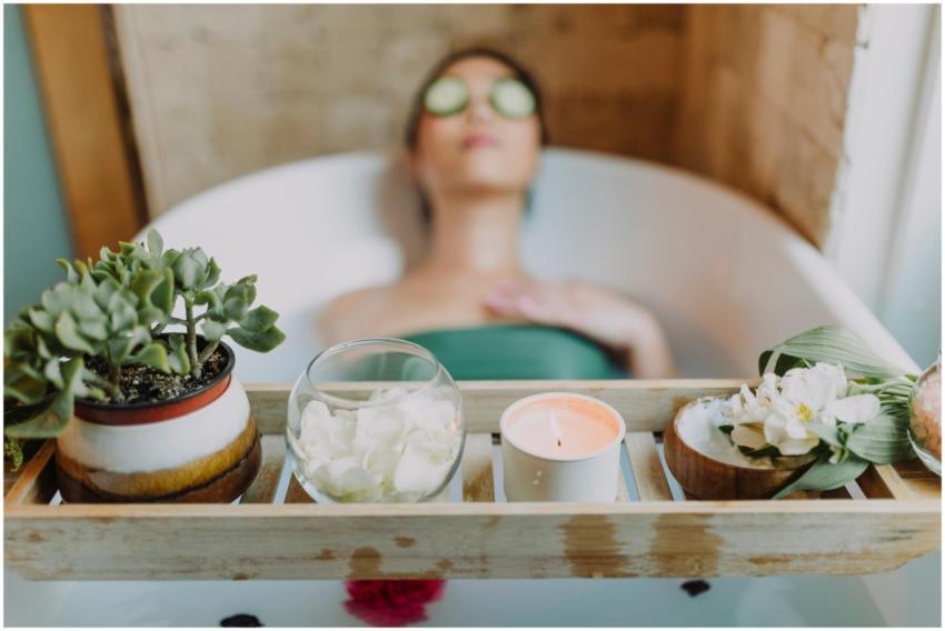 Woman relaxing in a bathtub with a candle and plan