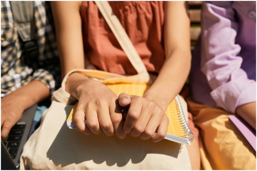Close-up of child's hands holding a notebook outdo