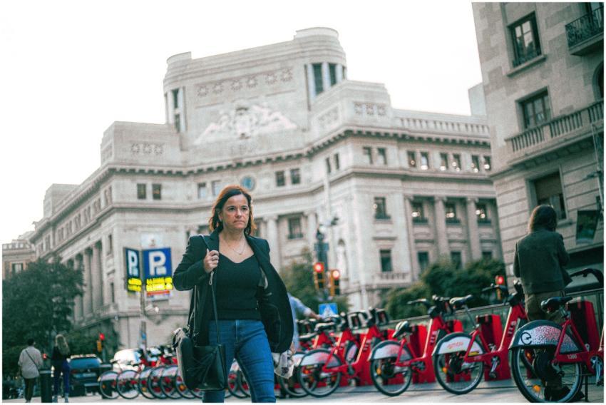 Woman walks past a city bike station near historic