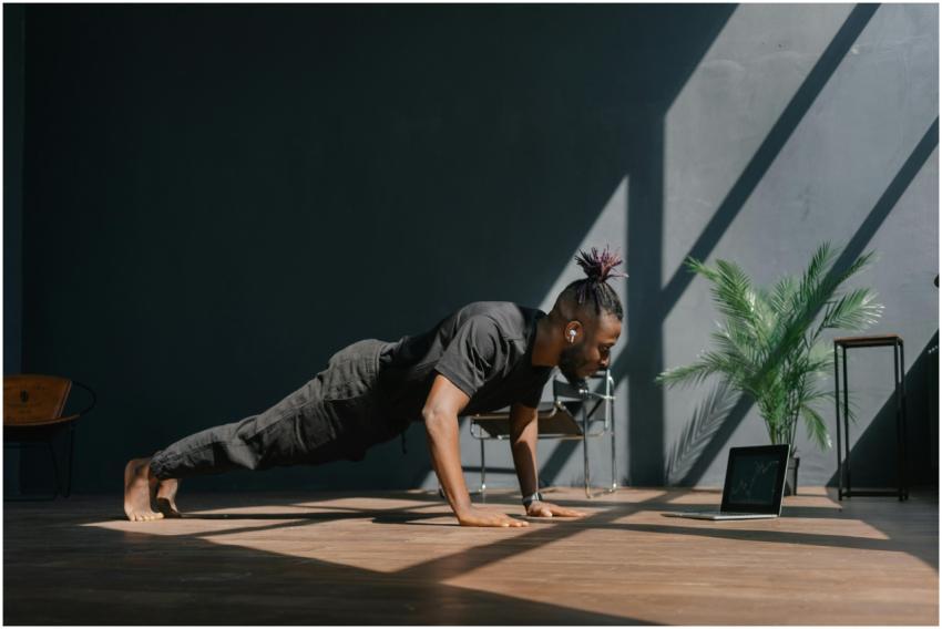 An adult man doing push-ups indoors, guided by a l