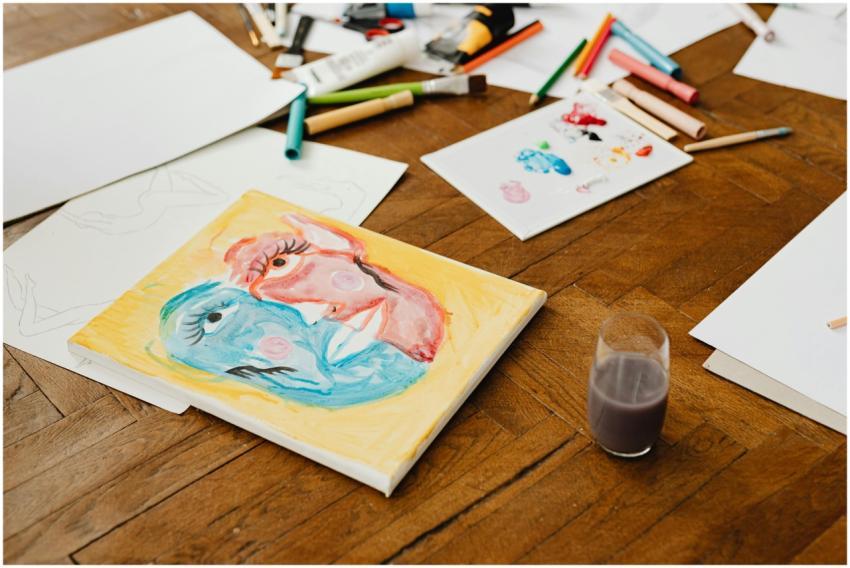Art supplies scattered on a wooden floor, featurin