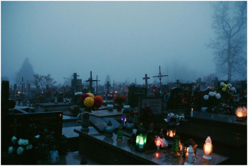 A foggy cemetery at night illuminated by candlelig