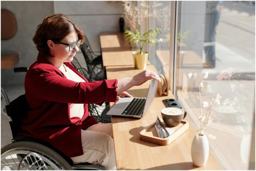 Woman in wheelchair working on a laptop in a brigh