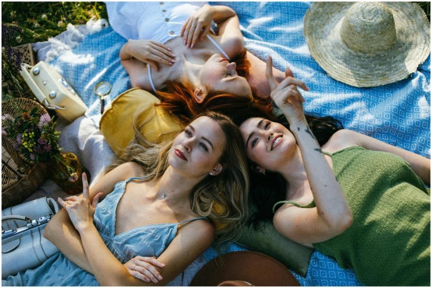Three women enjoying a picnic, lying on a blanket,