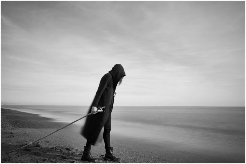 A solitary person walks along a desolate beach in