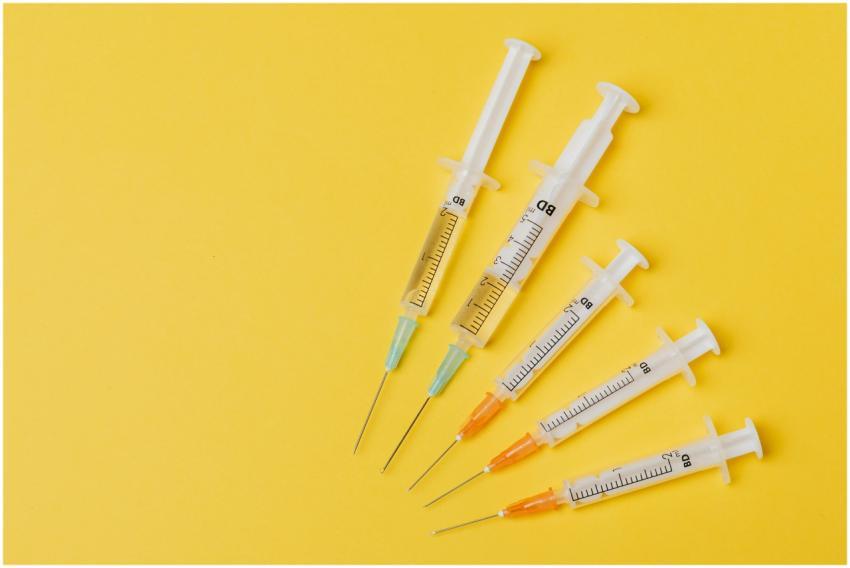 Overhead view of five syringes arranged on a yello