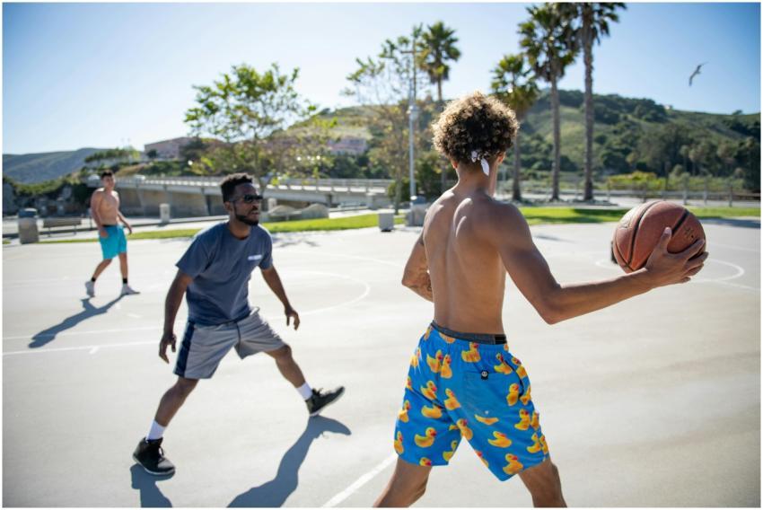 Young men play basketball on a sunny court in Avil