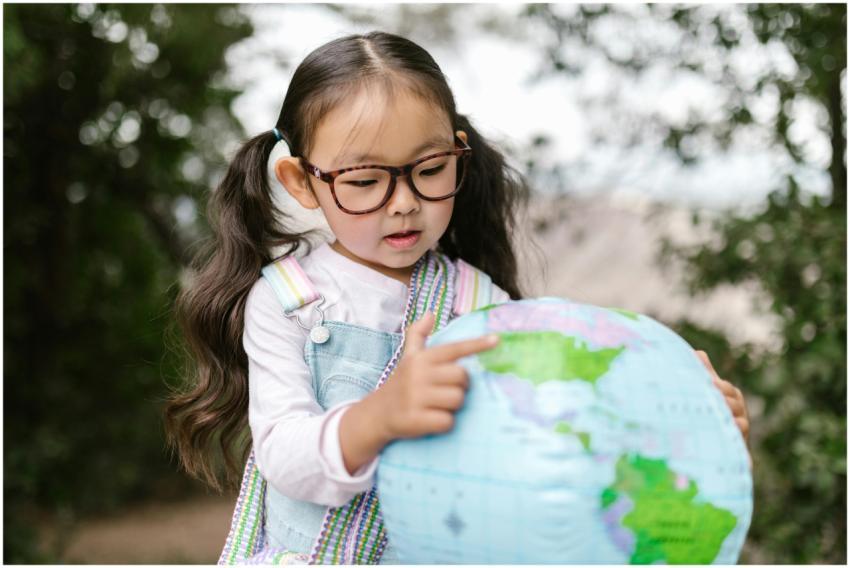 Curious child with glasses points to a globe outdo