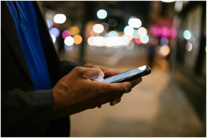 Close-up of a man using a smartphone on a busy cit