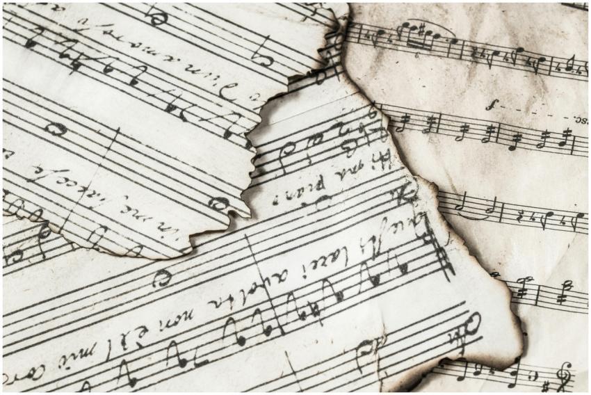 Close-up of aged, burnt music sheets displaying mu