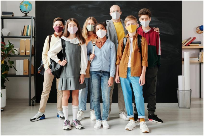 Group of students and teacher in masks standing in