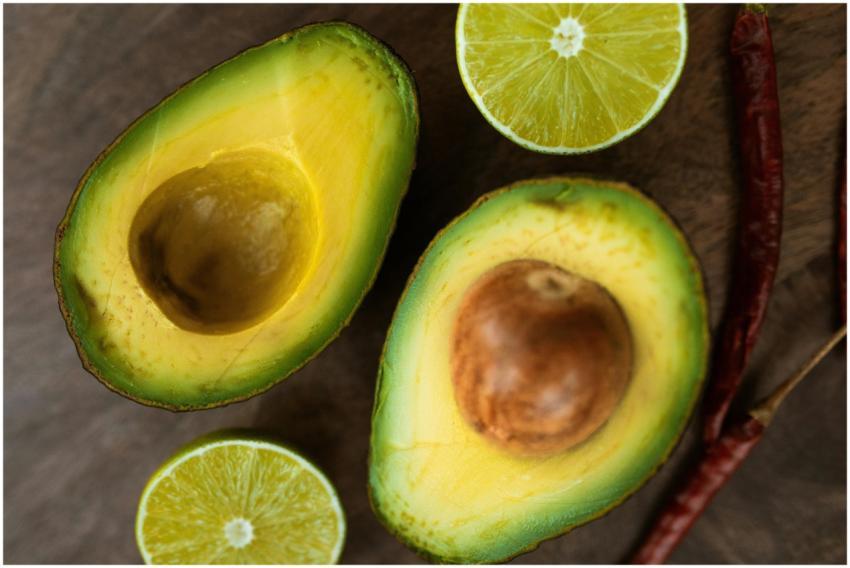 Sliced avocado and lime with chili peppers on a wo