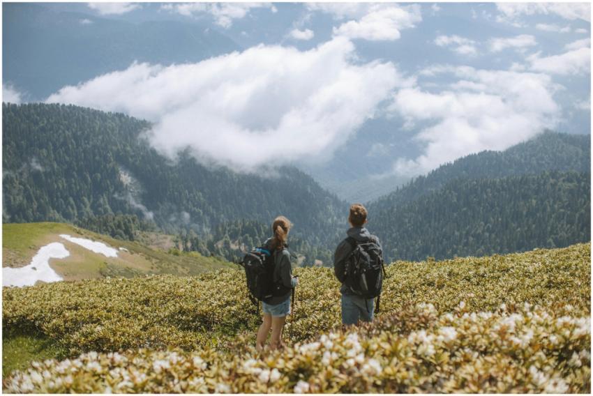 Two hikers with backpacks admire a stunning mounta
