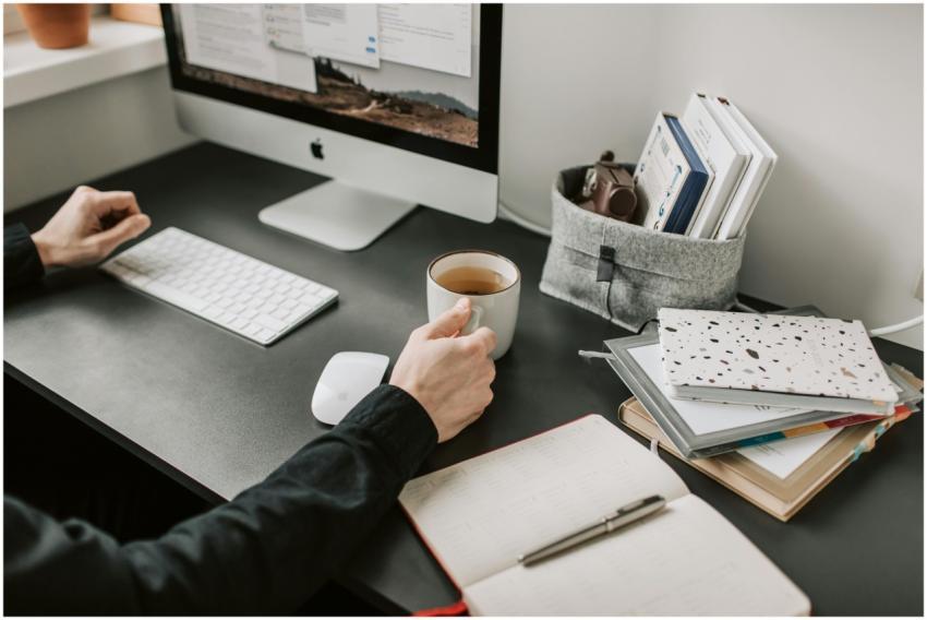 Man sipping coffee at a modern workspace with comp