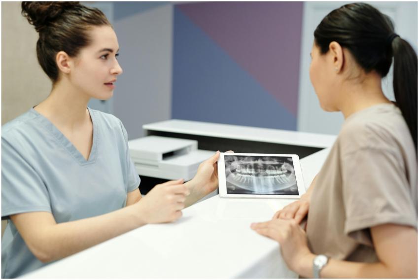 A dentist explains X-ray results to a patient usin