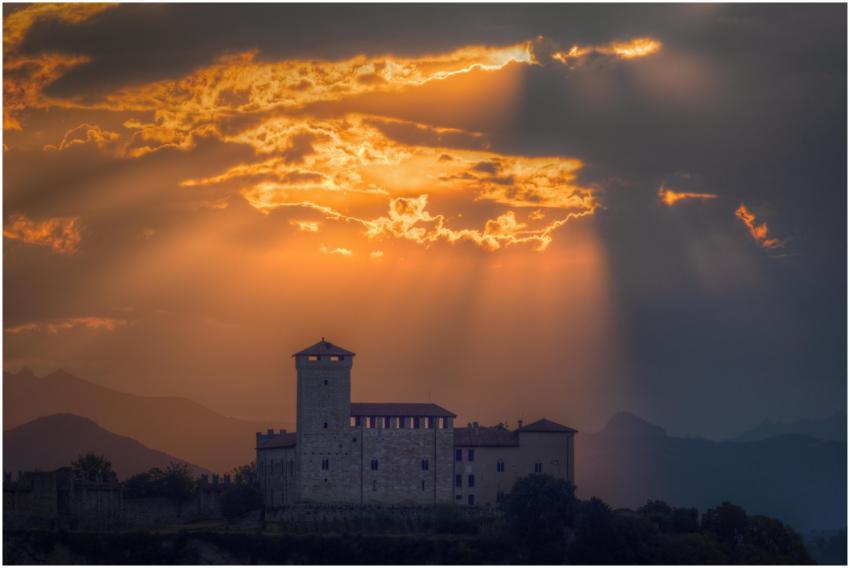 A historic castle silhouetted against a vibrant su