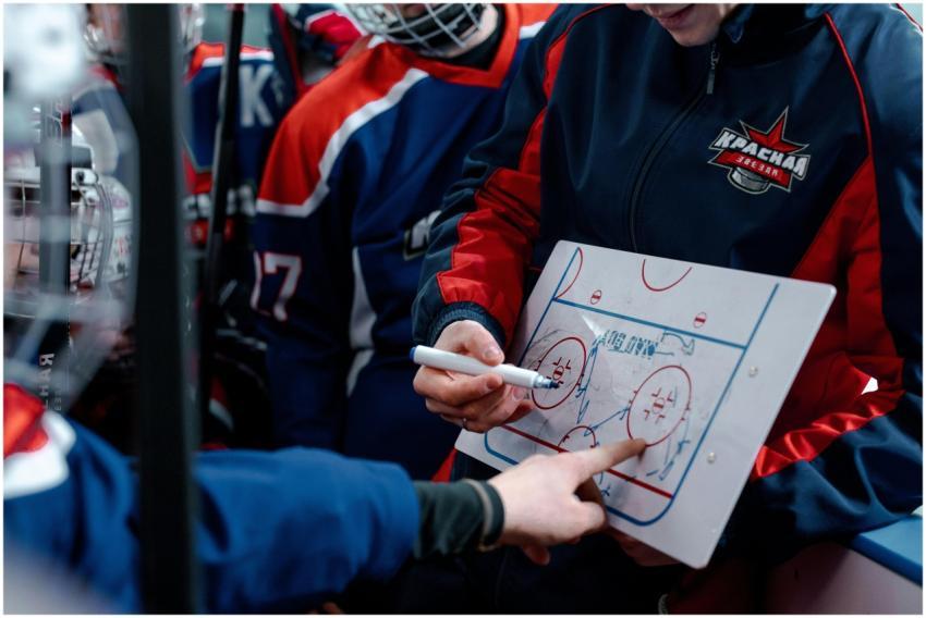 Hockey coach discussing tactics on a board with pl