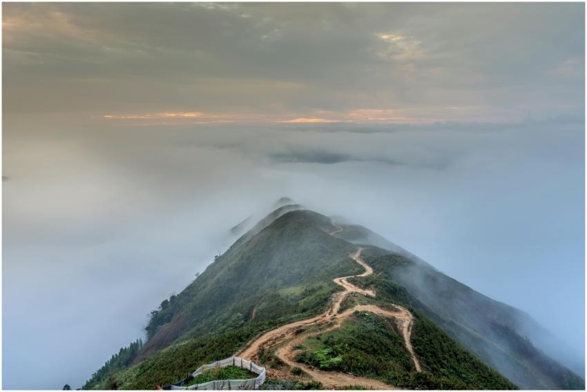 A winding path on a mountain peak enveloped in mis