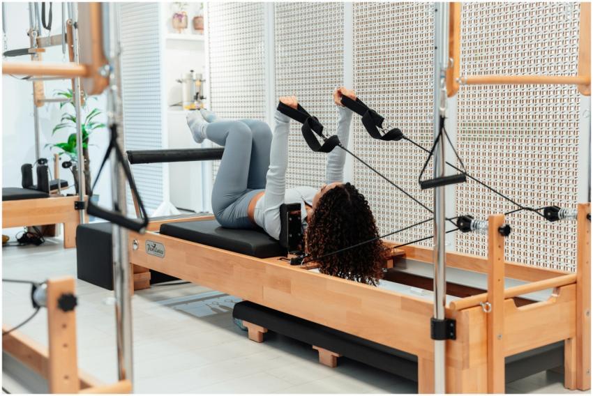 A woman practicing pilates on a reformer machine i