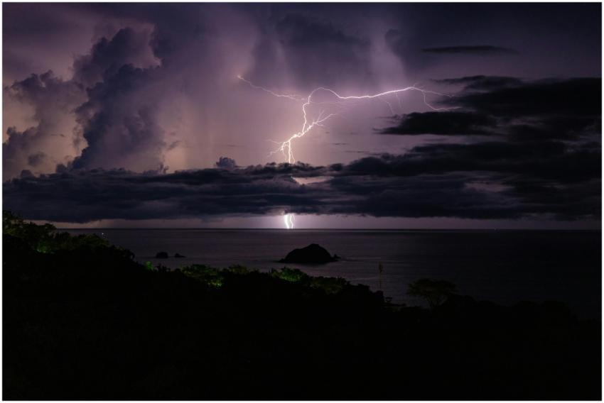 Powerful lightning illuminates a dark ocean scene