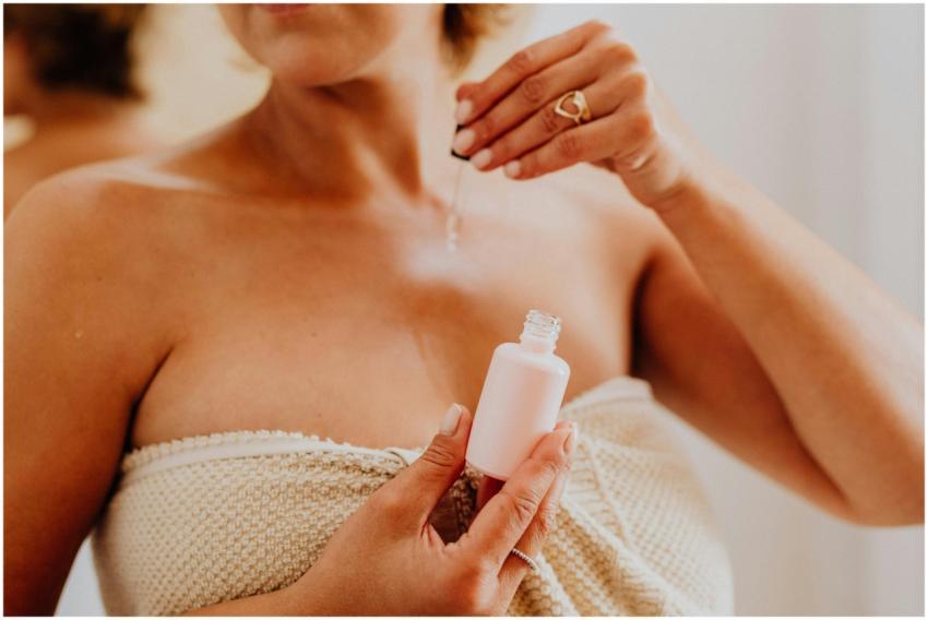 Close-up of a woman applying serum to her skin, en