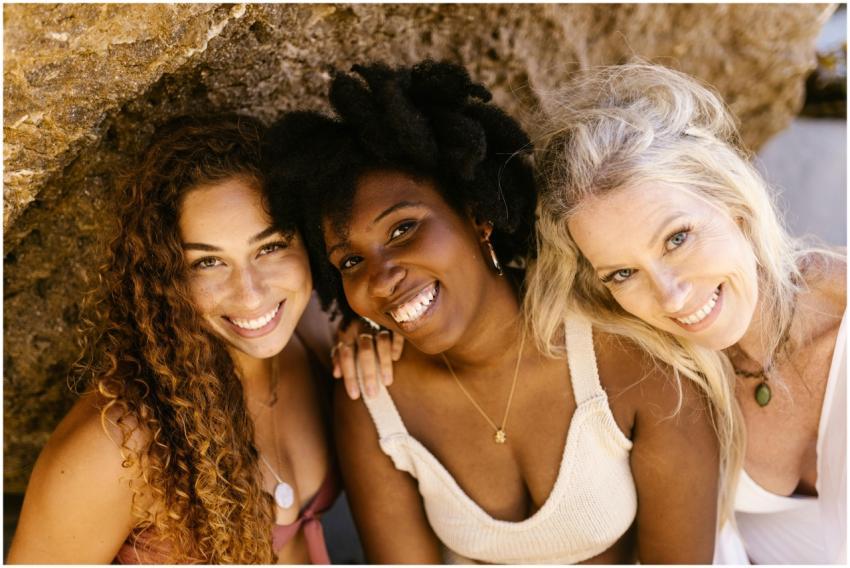 Three diverse women smiling warmly at the camera,