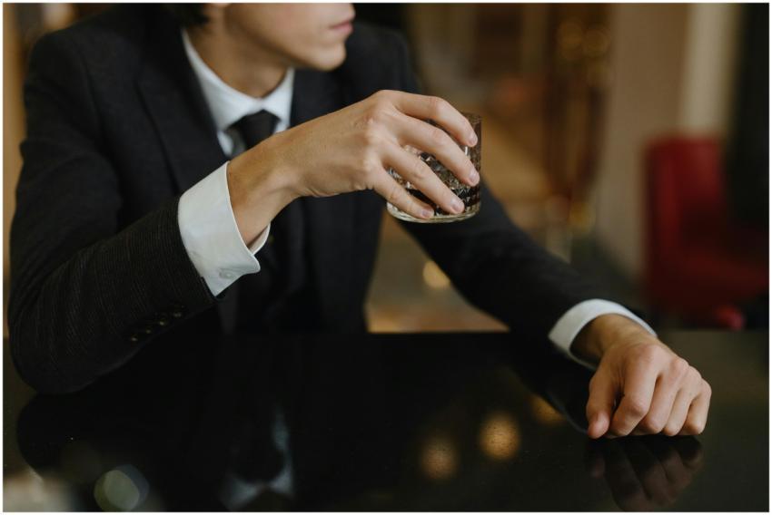 A man in a suit holding a whisky glass at an elega