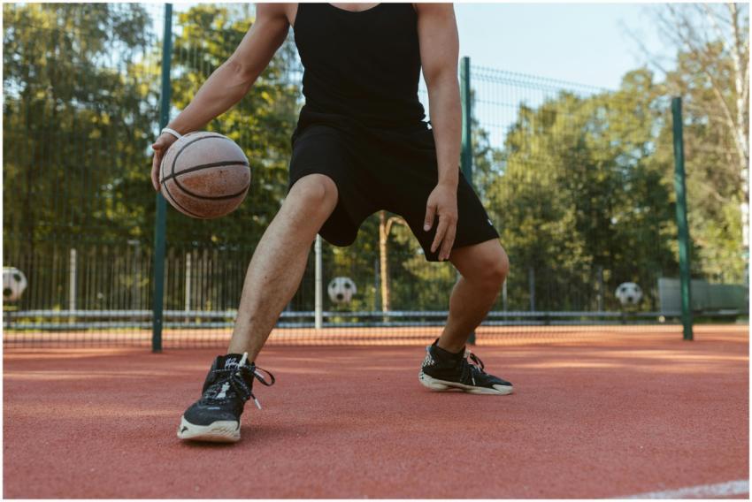 Athlete dribbling basketball on outdoor court. Per