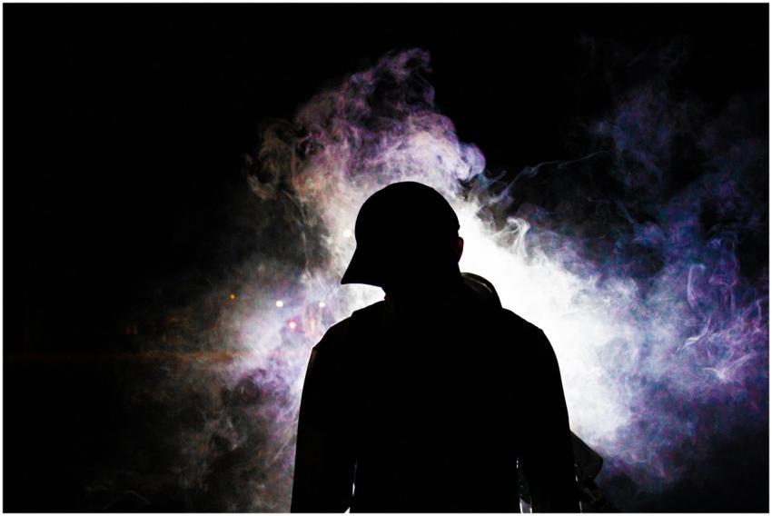 A dramatic silhouette of a man in a hoodie envelop