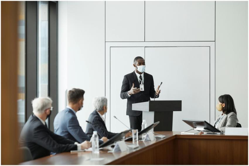 Business professionals in masks hold a meeting ind