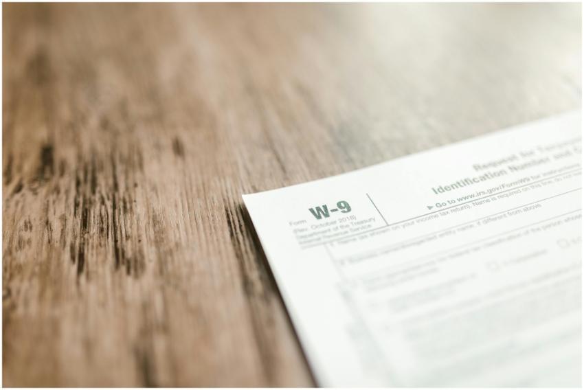 A close-up of a W-9 tax form placed on a wooden de