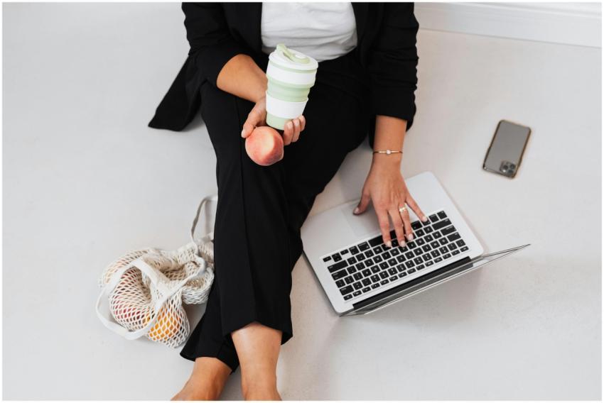 Businesswoman seated with laptop, peach, and reusa