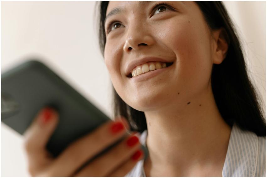 Close-up of a young woman smiling while using a sm