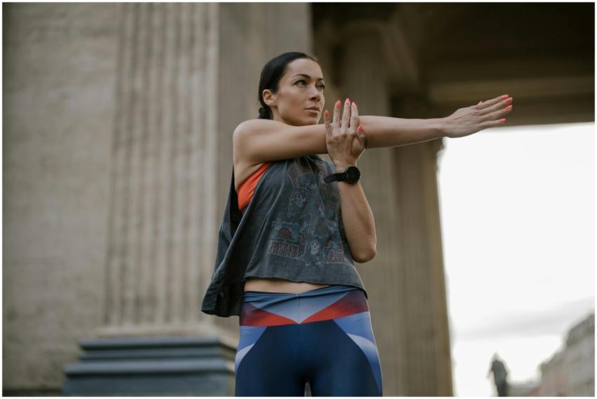 Athletic woman stretching her arms outdoors agains