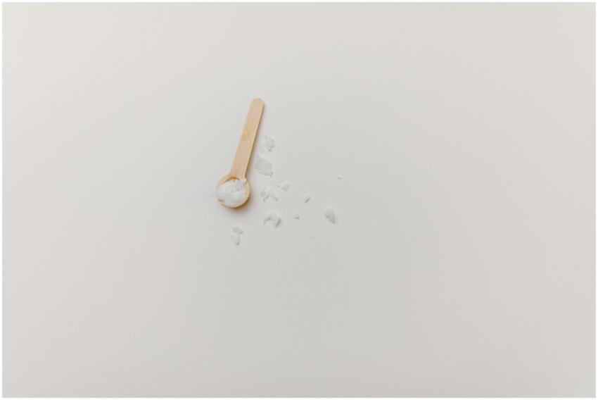 A wooden spoon with salt on a white background, of