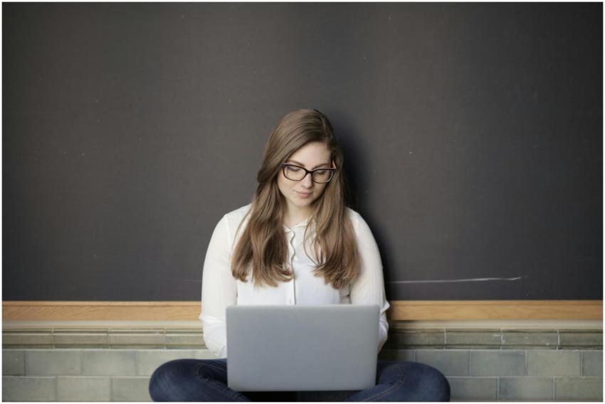 A young woman sitting indoors using a laptop, embo