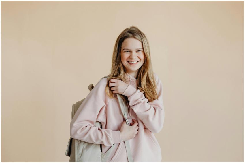 Happy teenage girl with a backpack and pink sweate