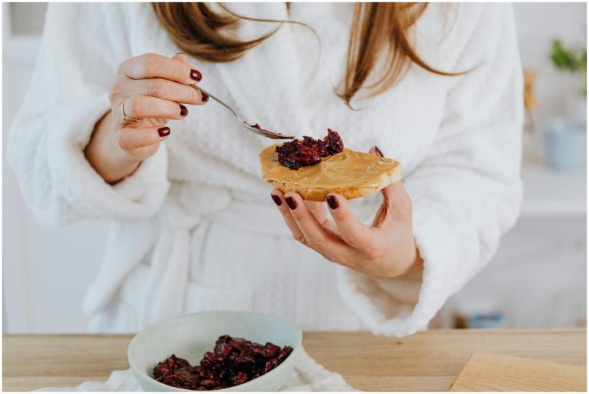 Close-up of a woman spreading jam on peanut butter
