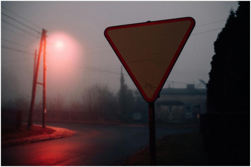 A foggy street scene at night with a triangular tr
