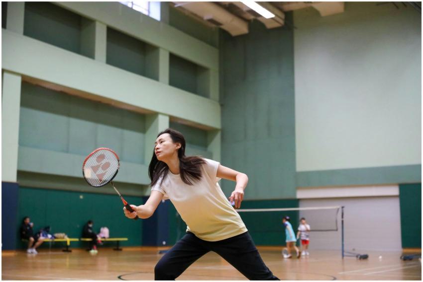 A female athlete playing badminton indoors, focuse