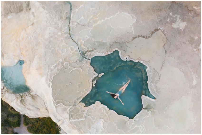 A woman swims in a natural turquoise pool against