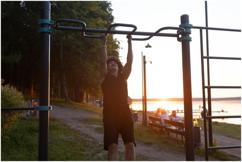 A man working out on pull-up bars in a park during