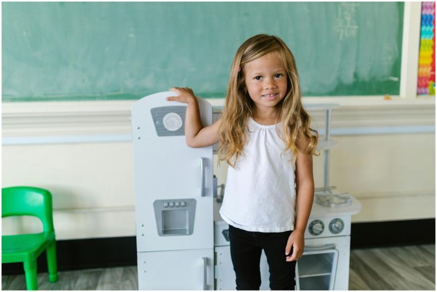 A cheerful young girl stands in a classroom near a