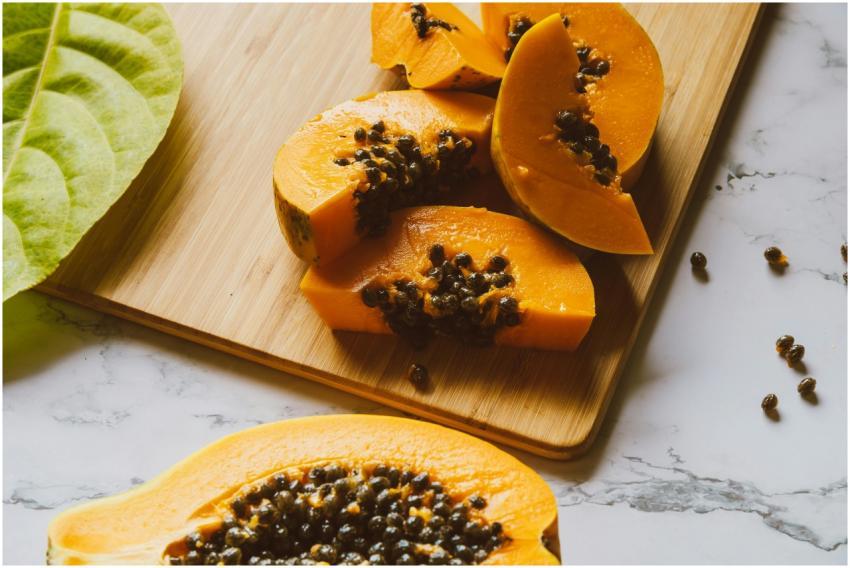 Close-up of fresh papaya slices with seeds on a wo