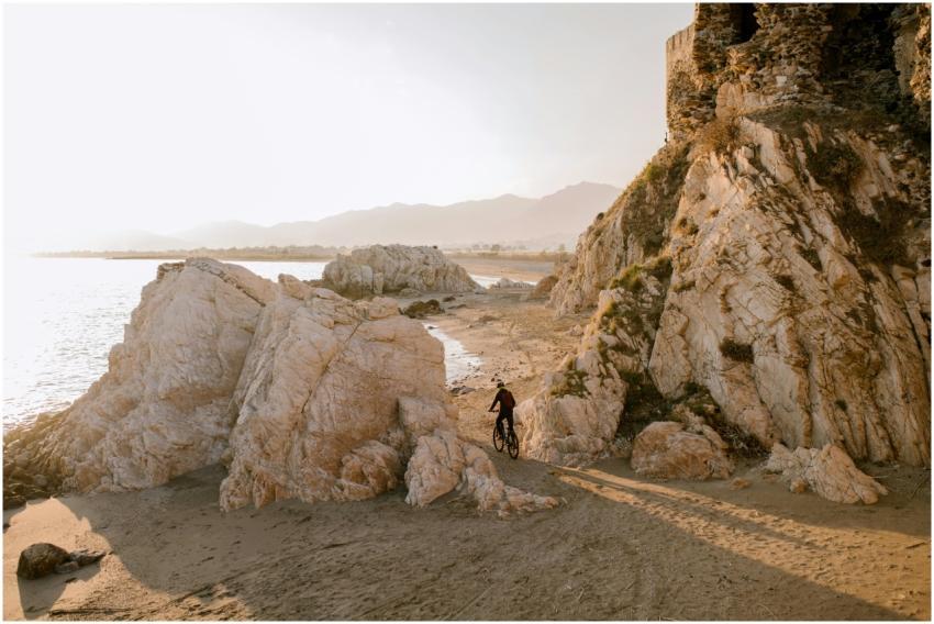 A cyclist navigates rocky coastal terrain by the b