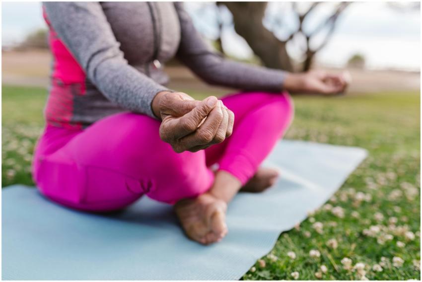 A senior woman meditating on a yoga mat outdoors,