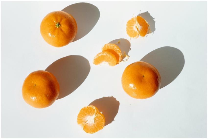 Bright and fresh mandarins with slices casting dra